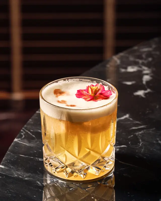 A cocktail in a cut-glass tumbler on dark marble