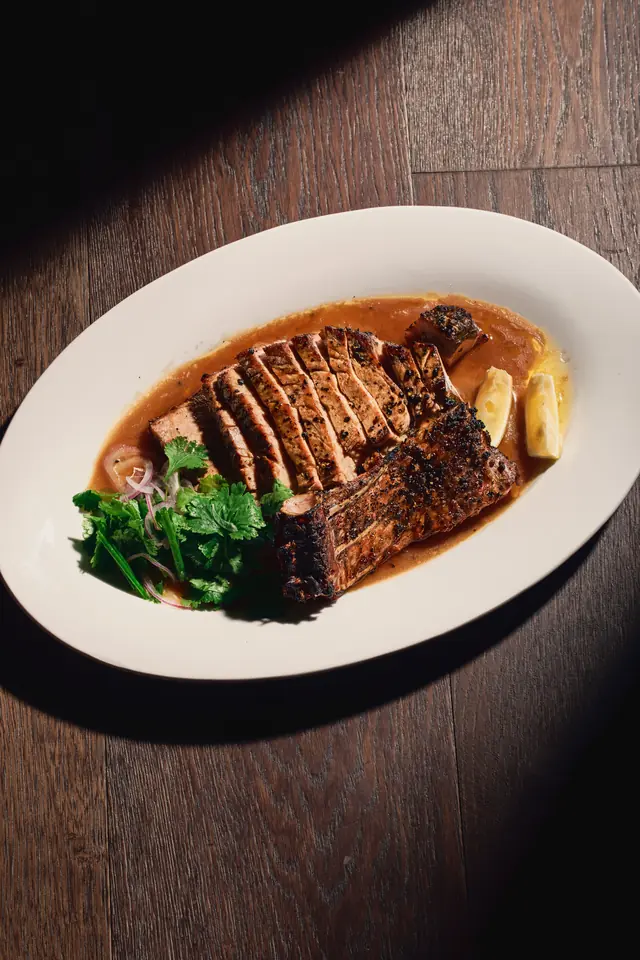 Gensan tuna porterhouse, seared and sliced, on a white plate